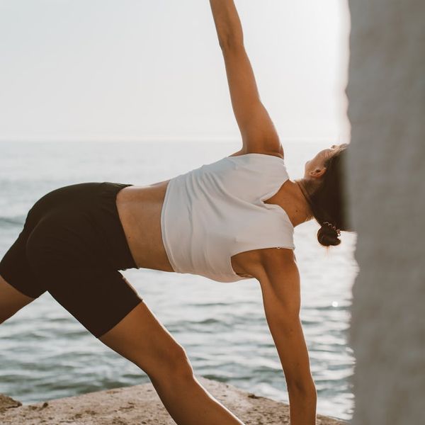 Person stretching gently outdoors during sunrise.