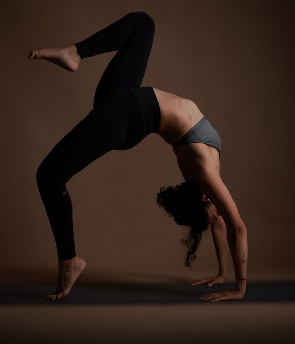 Woman in a calm yoga pose against a dark background.